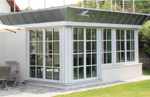 Angebauter Wintergarten mit weißen Sprossenfenstern