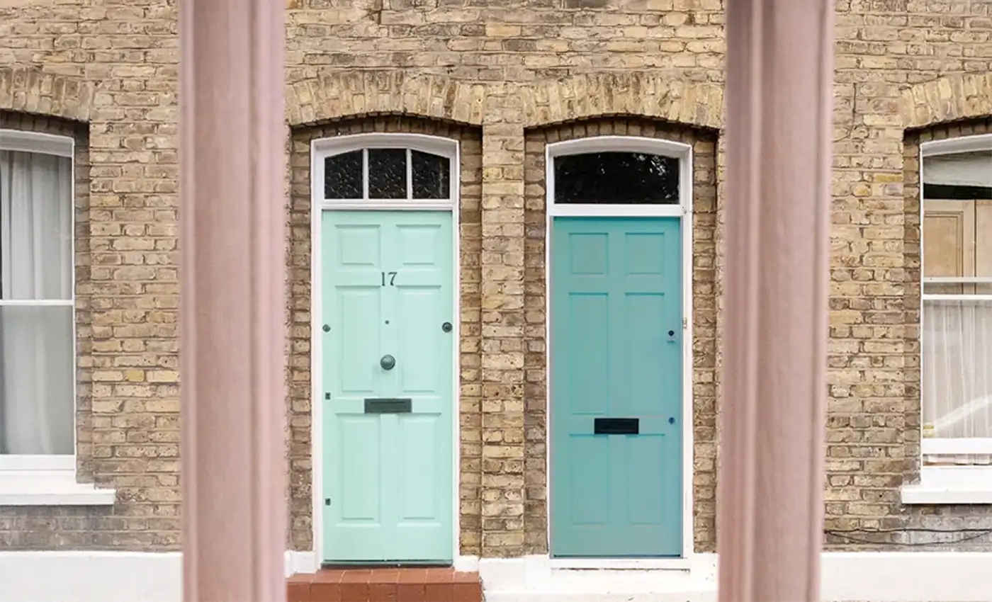 Zwei Holztüren in türkis an einem gemauerten Gebäude